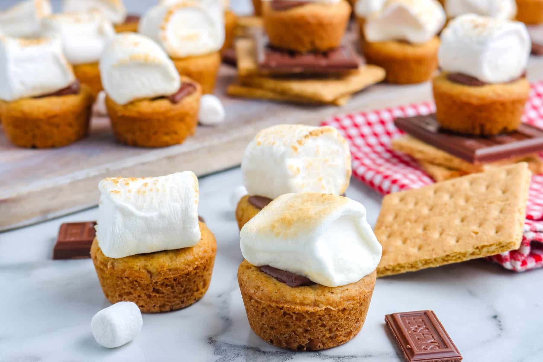 All of the s'more bites on a counter and on a wooden board.