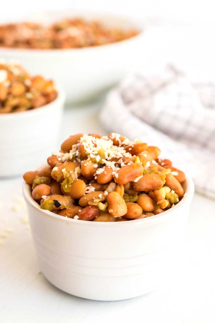 Green chile pinto beans served in white bowls.