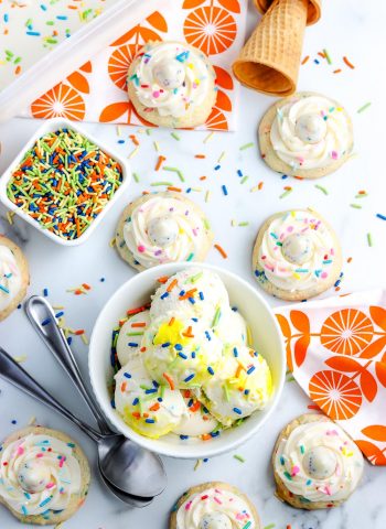 An overhead picture of Funfetti ice cream and birthday cookies on a table with sprinkles.