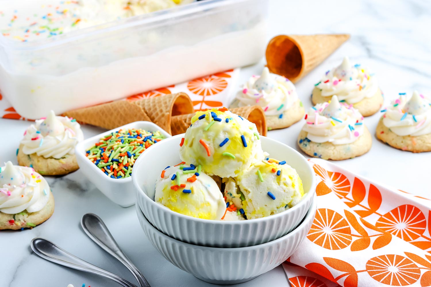Funfetti ice cream in white bowls with birthday frosted cookies in the background.
