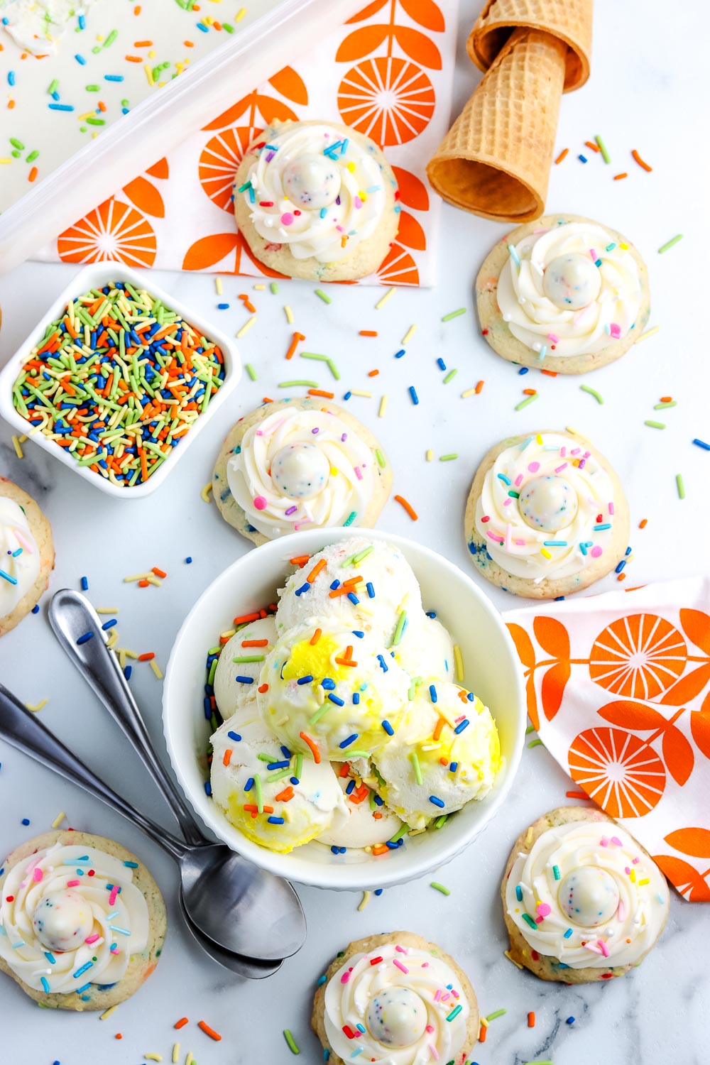 An overhead picture of Funfetti ice cream and birthday cookies on a table with sprinkles. 