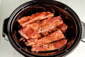 Place the rubbed ribs inside of the slow cooker.