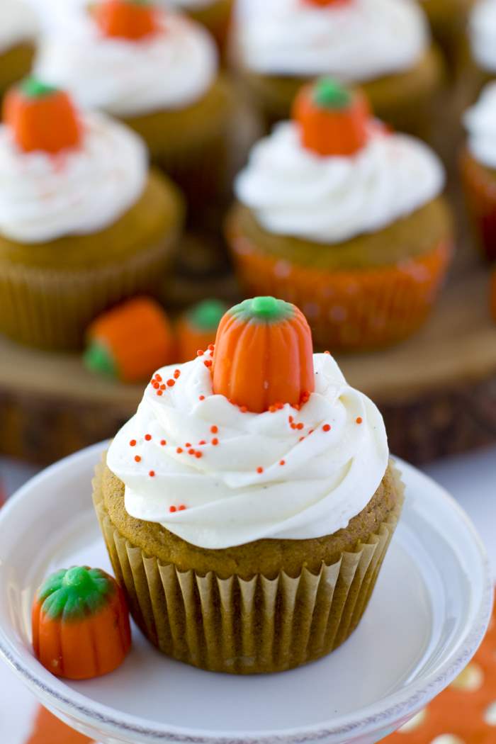 A close-up of a pumpkin cupcake on a plate with marshmallow buttercream