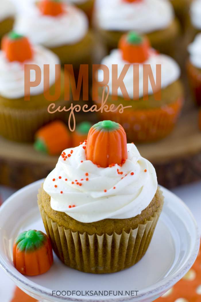 A pumpkin cupcake on a plate with more in the background and text overlay for Pinterest