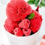 Raspberry Sorbet in a white dish garnished with fresh raspberries and mint.