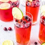 Glasses filled with Cranberry Mocktail and garnished with cranberries and limes.