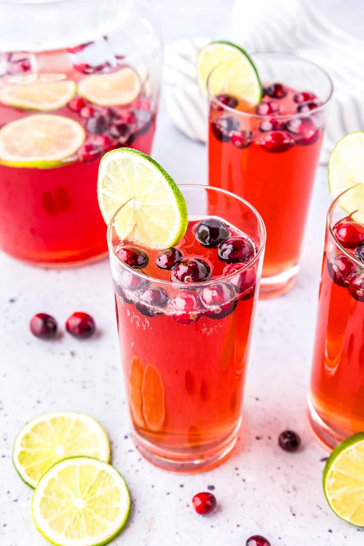 Glasses filled with Cranberry Mocktail and garnished with cranberries and limes. 