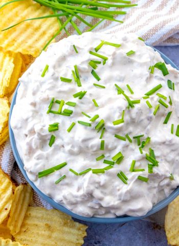 Overhead picture of onion dip in a blue bowl with chips surrounding it.