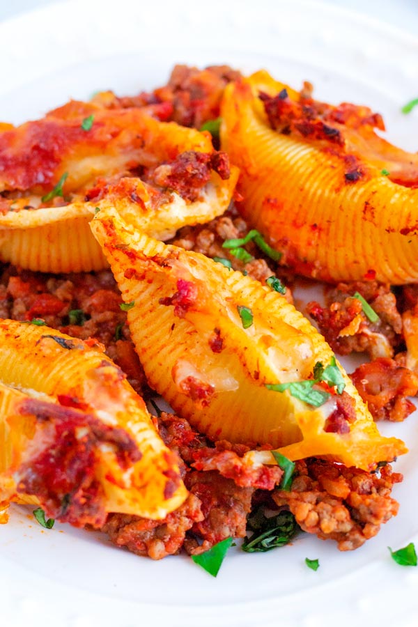 Close up picture of stuffed shells with meat sauce on a plate.