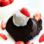 A slice of Dark Chocolate Pound Cake with strawberries and cream on top