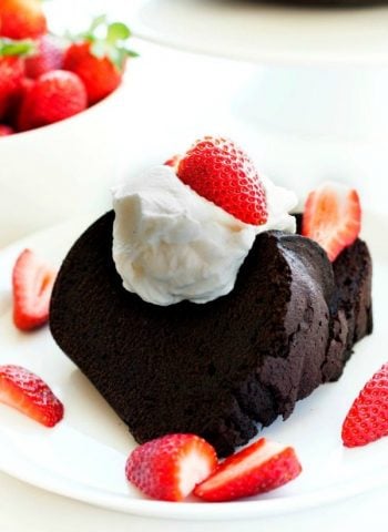 A slice of Dark Chocolate Pound Cake with strawberries and cream on top
