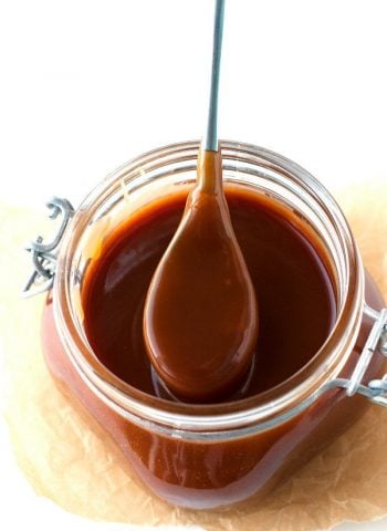 A spoonful of caramel sauce from a jar full of caramel
