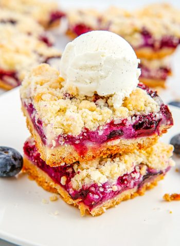 Two Blueberry Crumb Bars with a scoop of ice cream on top.