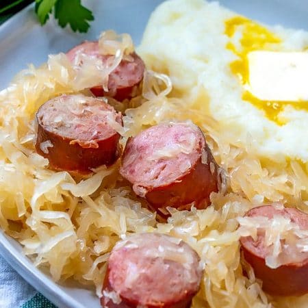 Close up picture of kielbasa kapusta on a serving place with mashed potatoes.