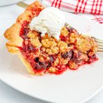 A close up picture of the finished Cherry Crumble Pie on a white plate.