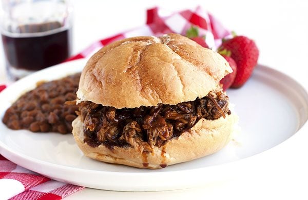 Close up picture of a pulled pork sandwich on a white plate. 