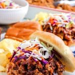 A picture of the pulled pork on a roll on a plate.