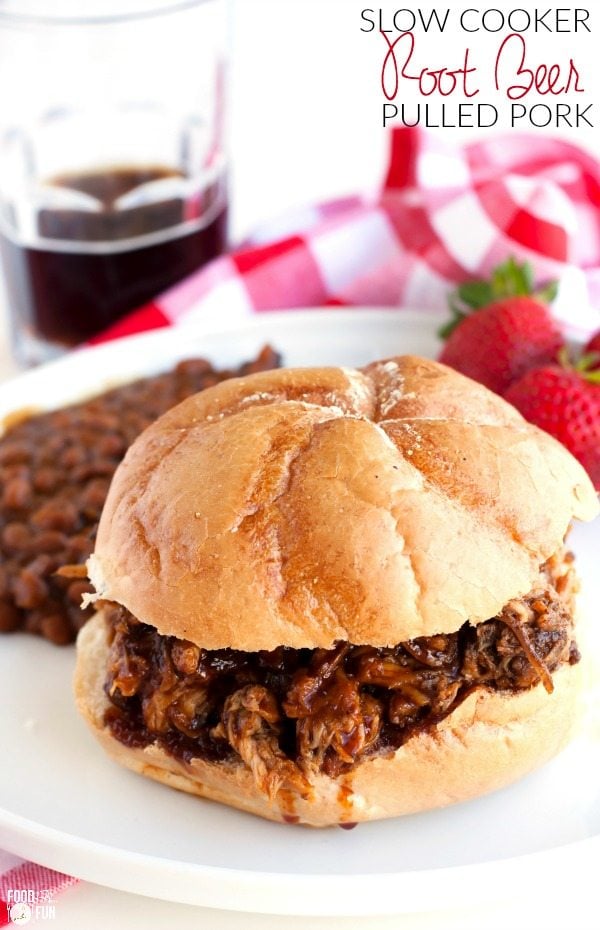 Root Beer Pulled pork on a kaiser bun that is on a white plate with baked beans. 