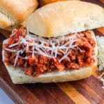A close-up picture of a finished beef bolognese sloppy joe on a wooden platter.