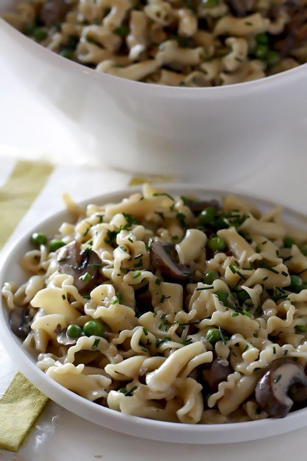 Pasta with mushrooms on a white plate and in a white serving bowl. 