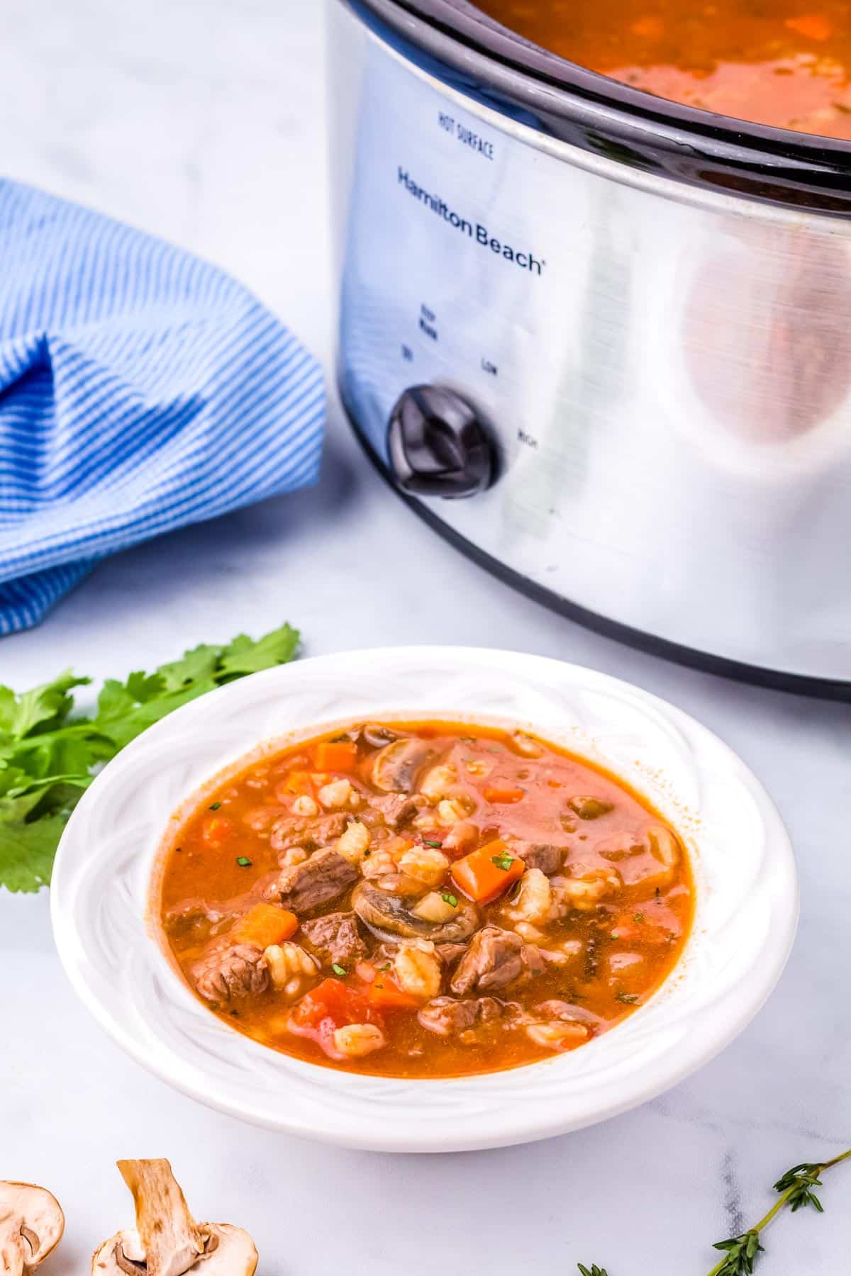 A white bowl full of slow cooker Beef and Barley Soup.