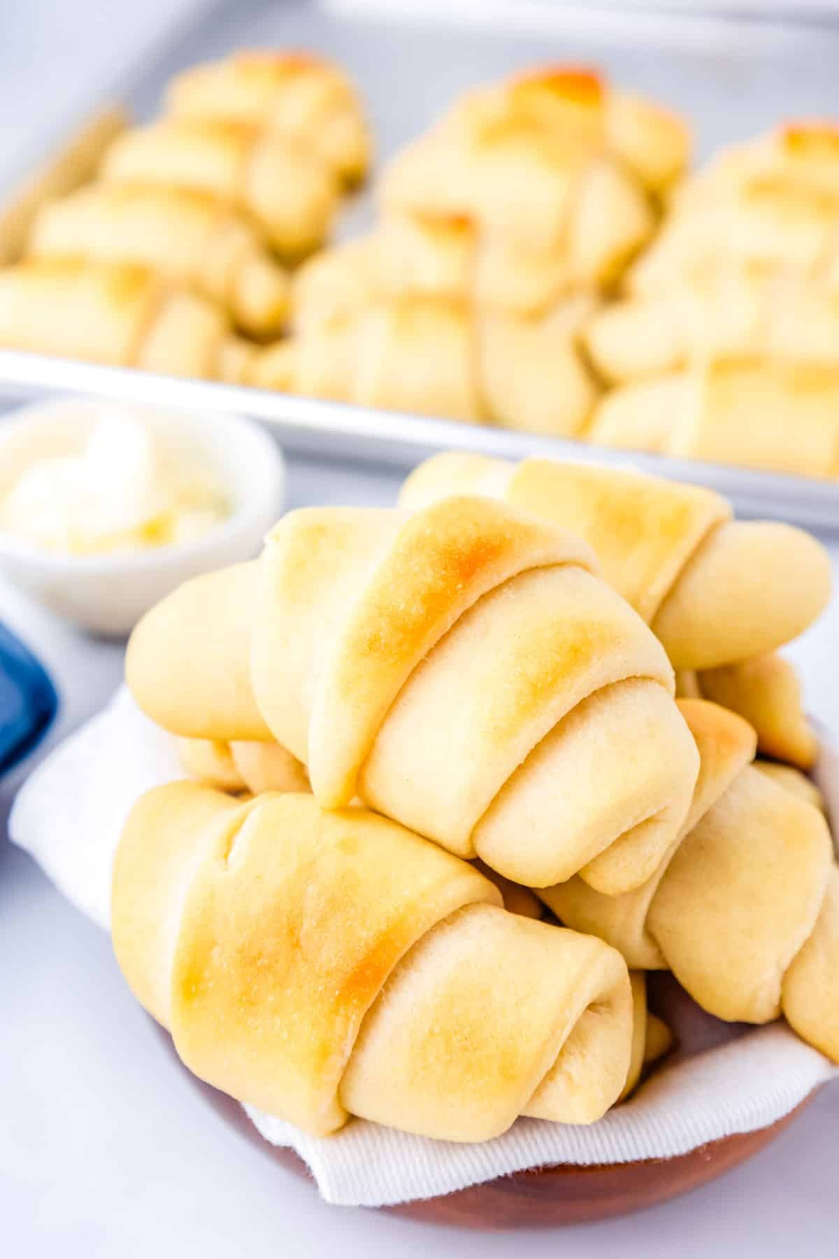 A pile of homemade Crescent Rolls on a white plate.