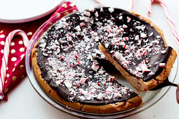 A slice of Peppermint Bark Sugar Cookie Pie being taken out of the pie plate. 