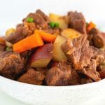 Beef stew in a white serving bowl.