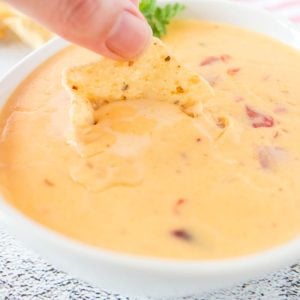 A chip dipping into the Chile Con Queso.