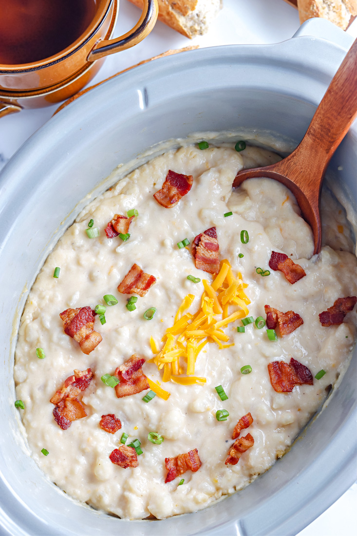 An overhead picture of the finished Slow Cooker Loaded Baked Potato Soup in a Crockpot garnished with bacon, cheese, and green onion.