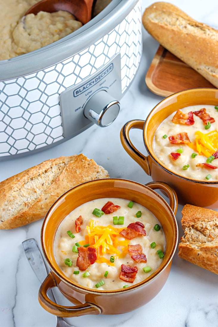 Slow Cooker Loaded Baked Potato Soup in soup bowls and in a Crockpot.