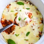 A spoon getting some baked ziti from a crockpot.