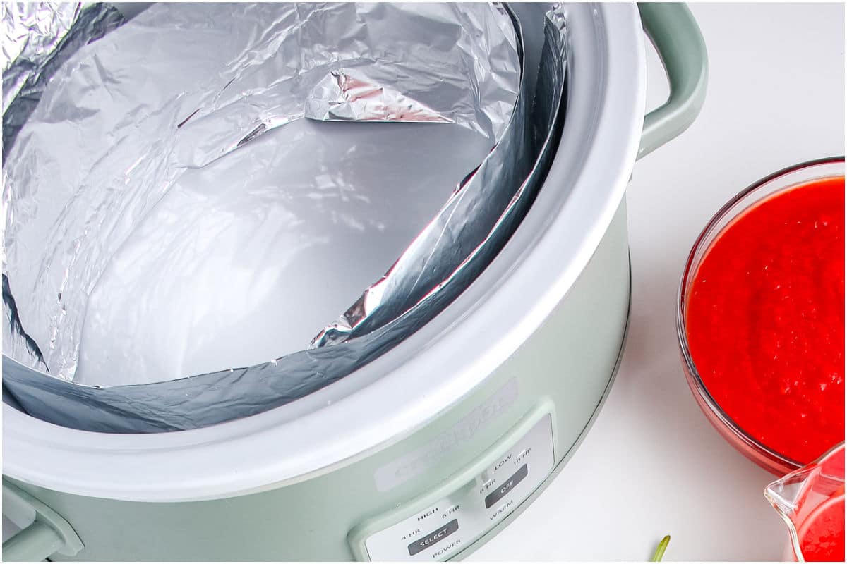 A crockpot lined with foil and sprayer with non-stick cooking spray.