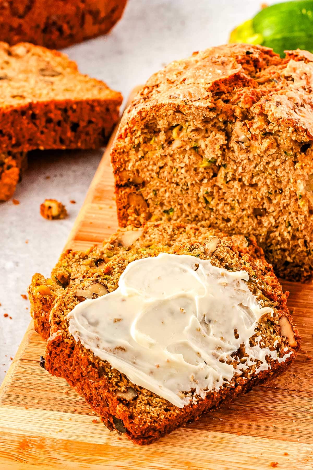 A loaf of moms zucchini bread with a slice cut from it and covered in butter.