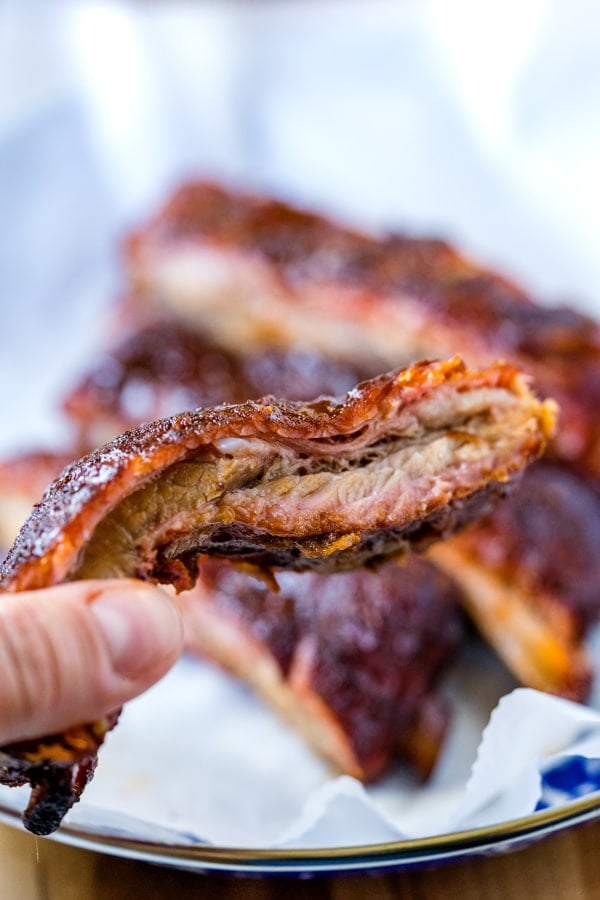 Close up of a smoked pork rib being held up close to the camera.