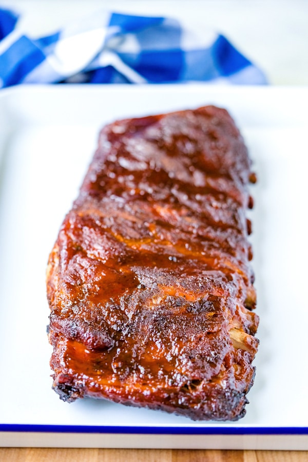 Smoked spare ribs rack on a white platter after it's fully cooker.