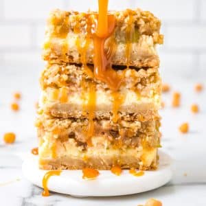 A close up of threee Caramel Apple Cheesecake Bars stacked on top of each other.