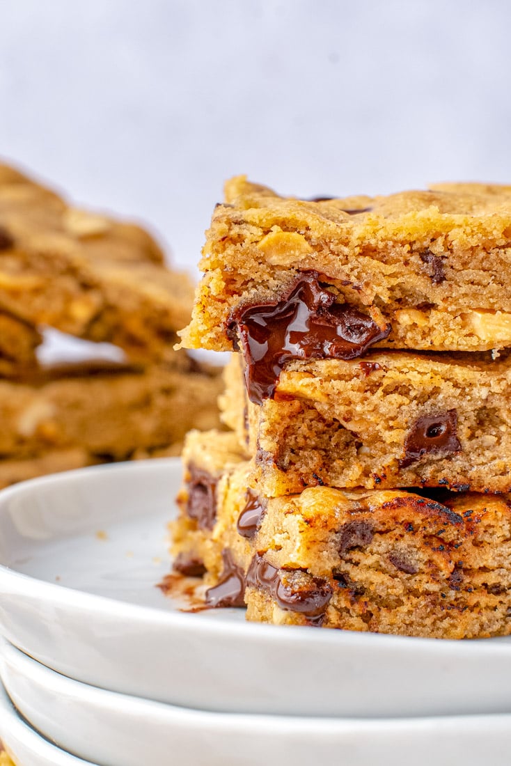 A close up of three Peanut Butter Cookie Bars stacked on each other with dripping chocolate coming out of one of them.