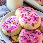 Round sugar cookie with pink frosting and rainbow sprinkles.