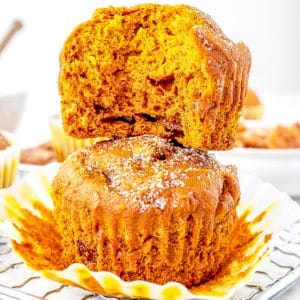 A close up if two pumpkin honey muffins stacked on top of each other with a bite taken out of one.