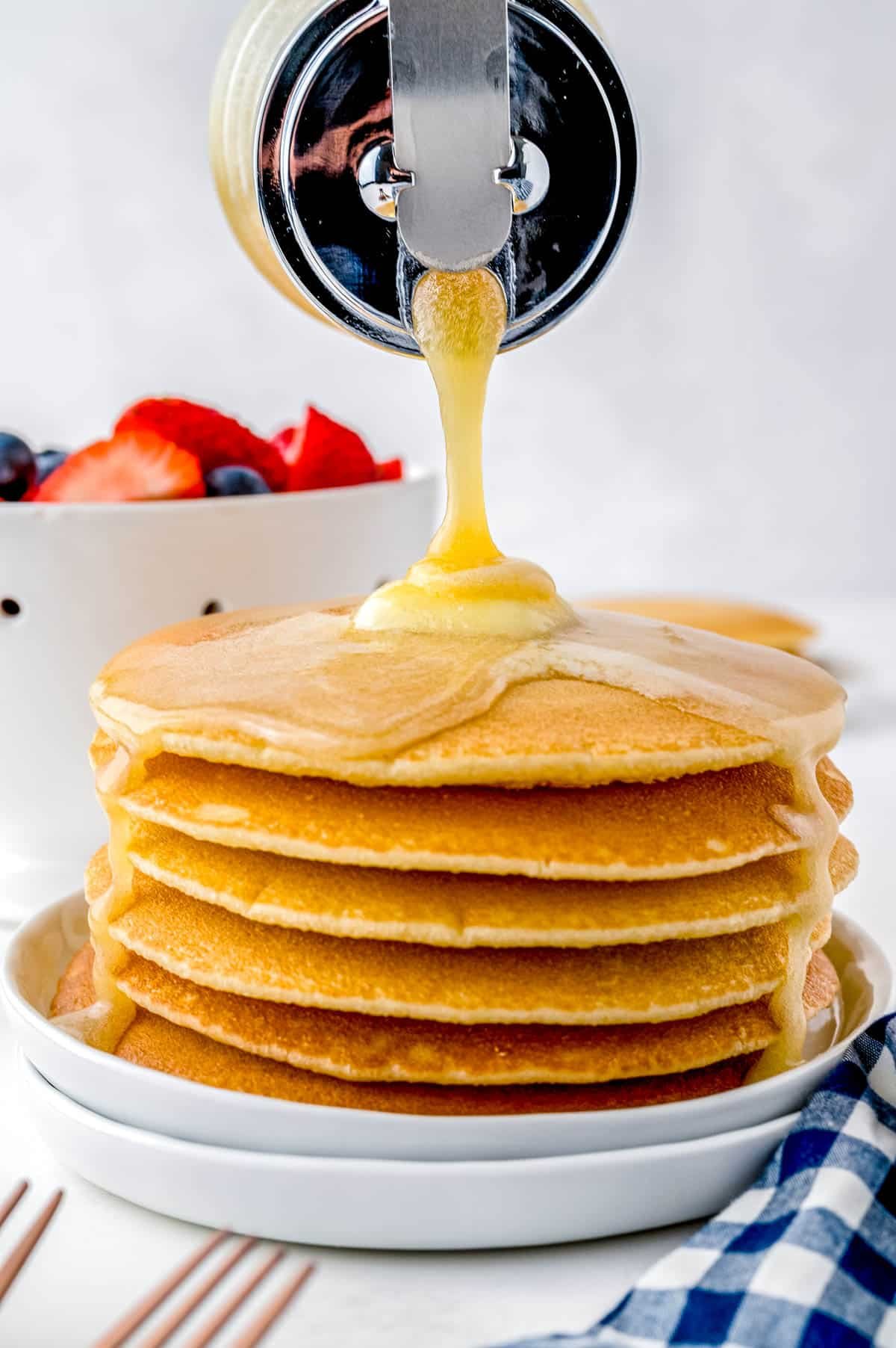 The finished Buttermilk Syrup recipe being poured over a stack of pancakes.