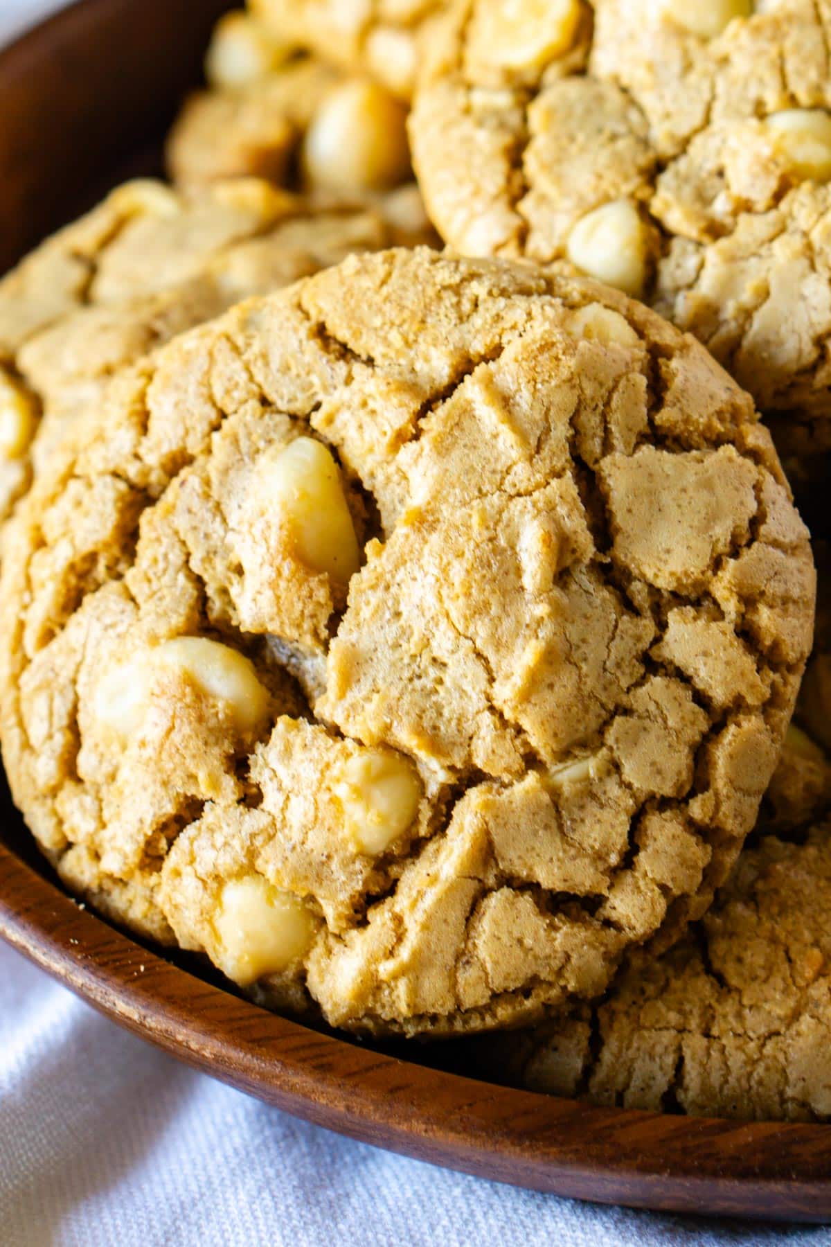 A macadamia nut cookie on a wooden tray.