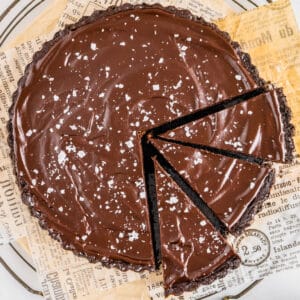 A closeup picure of the chocolate ganache tart with three slices cut into it