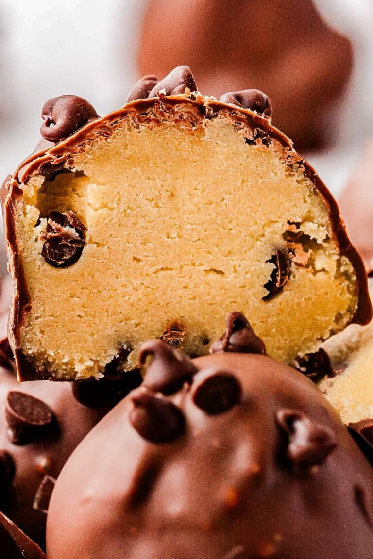 Cookie dough truffles in a pile and one cut in half so you can see the interior.