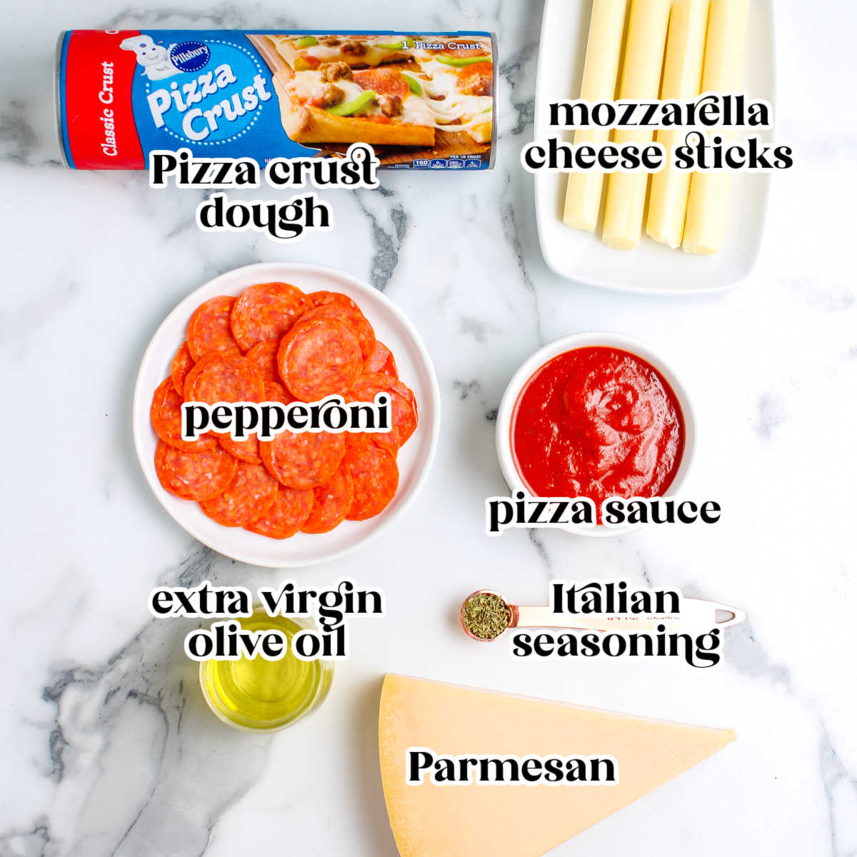 A flat lay of ingredients on a marble surface including a tube of Pillsbury pizza crust, four mozzarella cheese sticks, a plate of pepperoni slices, a bowl of pizza sauce, extra virgin olive oil, Italian seasoning, and a wedge of Parmesan cheese.