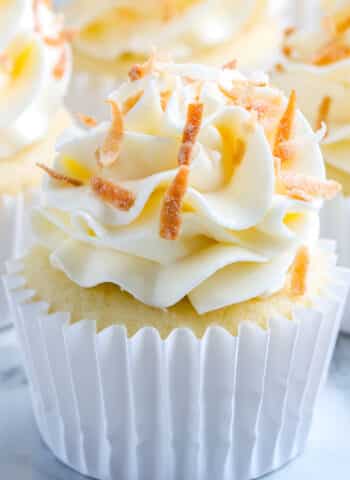 A close up of a finished Coconut Cupcakes that's garnished with toasted coconut.