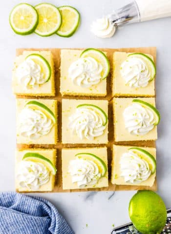 An overhead picture of nine Key Lime Pie Bars cut on a tabletop and garnished with whipped cream.
