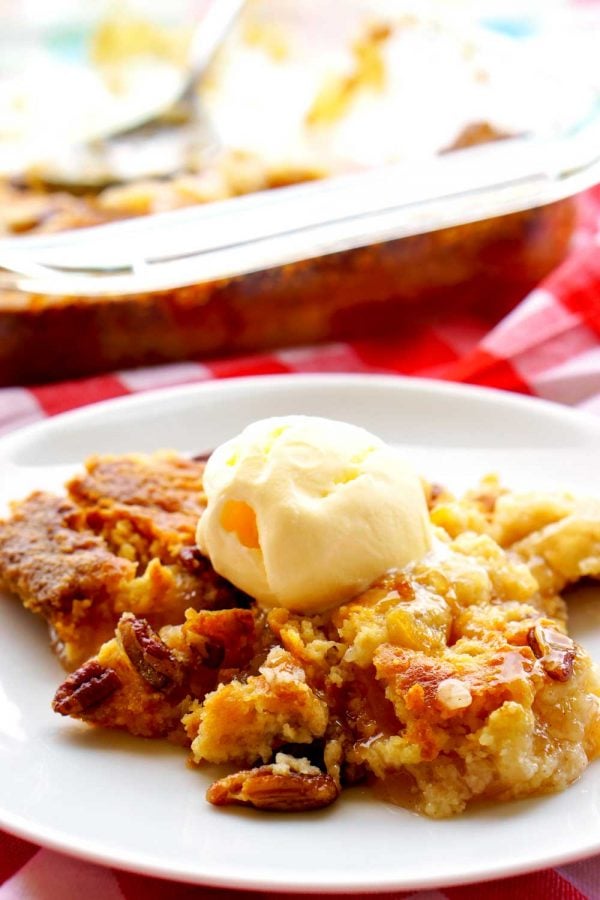 Apple dump cake on a white plate with a scoop of vanilla ice cream on top.