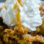 A close up picture of apple crisp with whipped cream and caramel sauce.