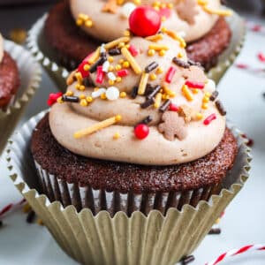 A frosted gingerbread cupcake with spriunkles on it.